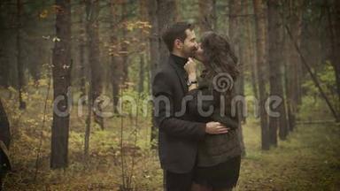 在森林里有个约会的快乐夫妻。 微笑的男人和女人站在树间互相拥抱